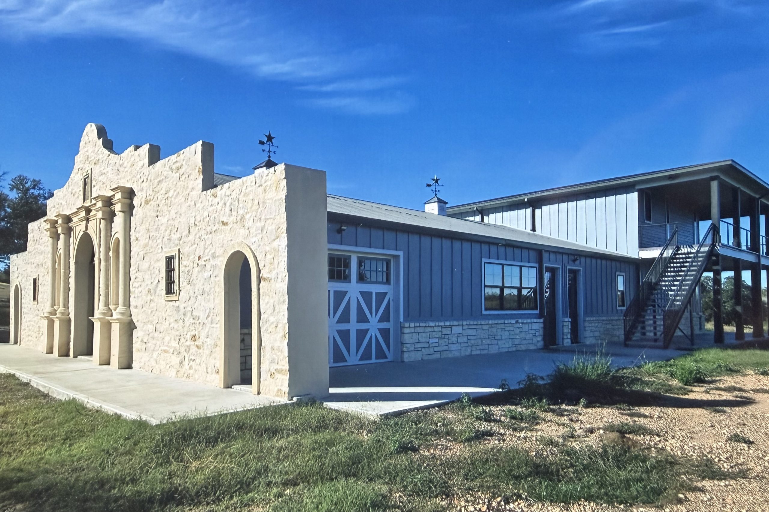 Side view of the Alamo Wall with the barndominium, stairs, and living quarters behind it, built by Cross Creek