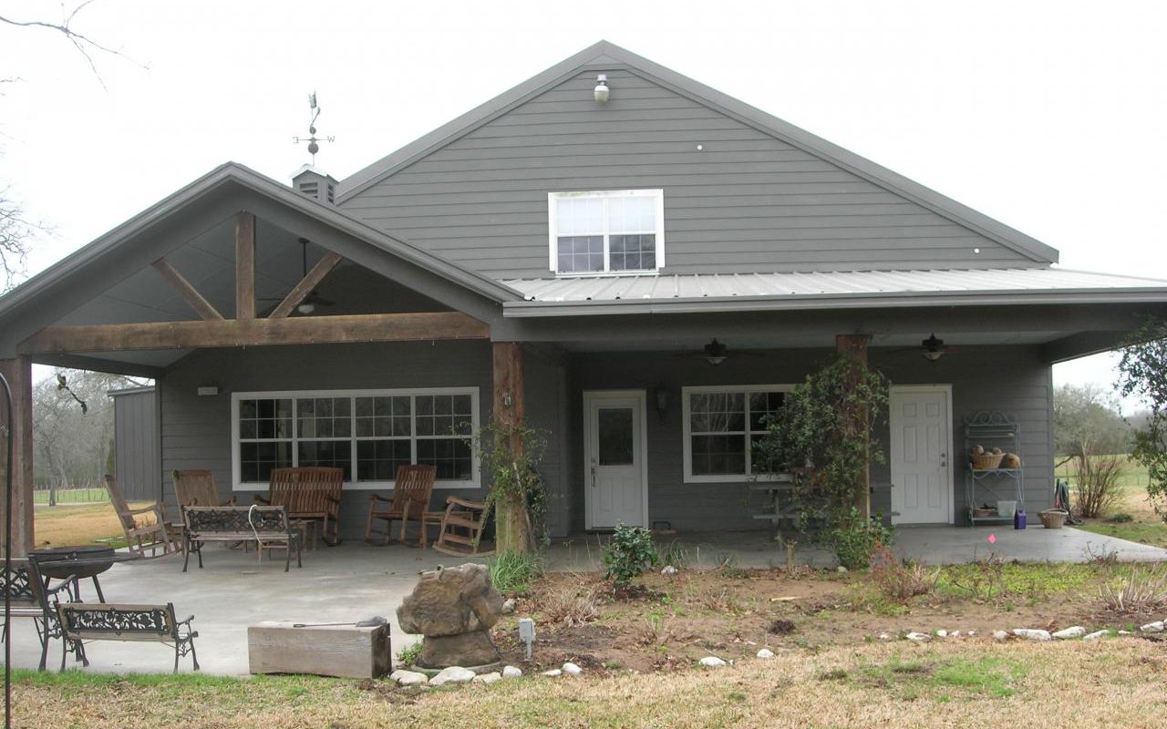 Gray board and batten barndominium with a cedar post porch, built by Cross Creek