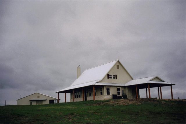 Metal-roof custom home and stable built together on ranch land