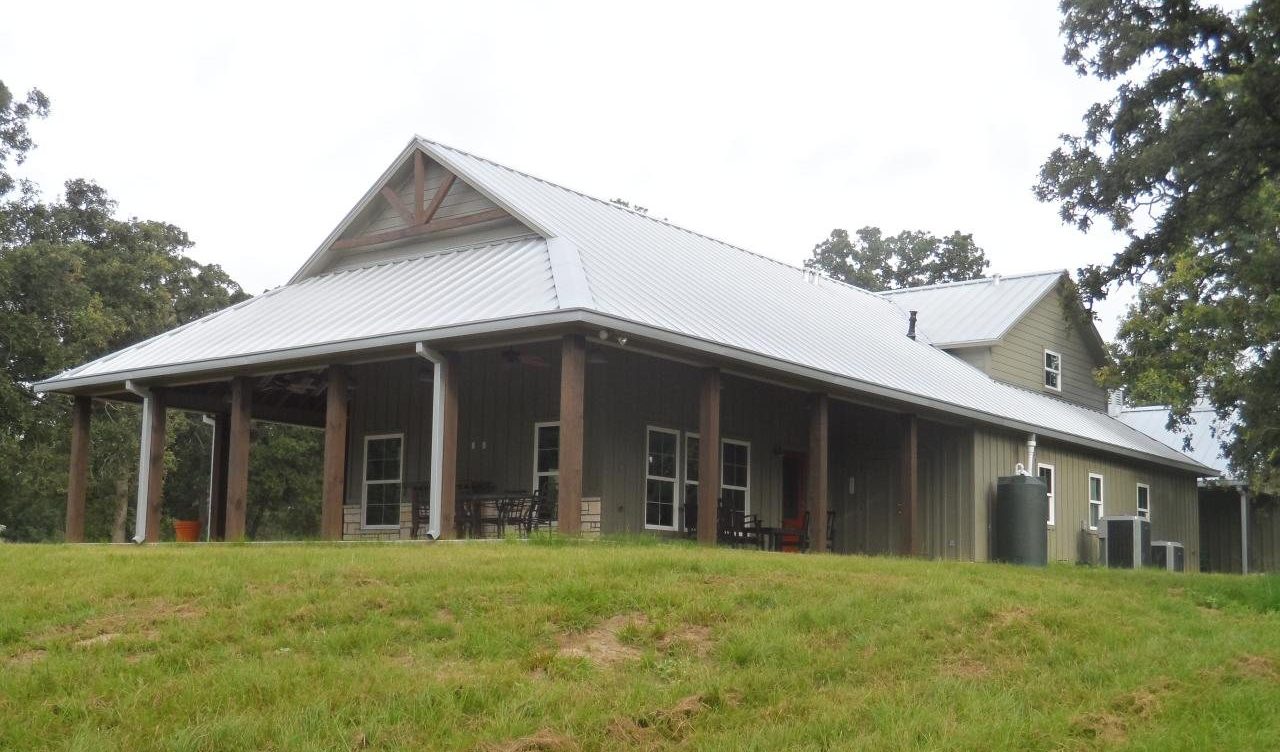 Custom barndominium with deep porches built on open acreage