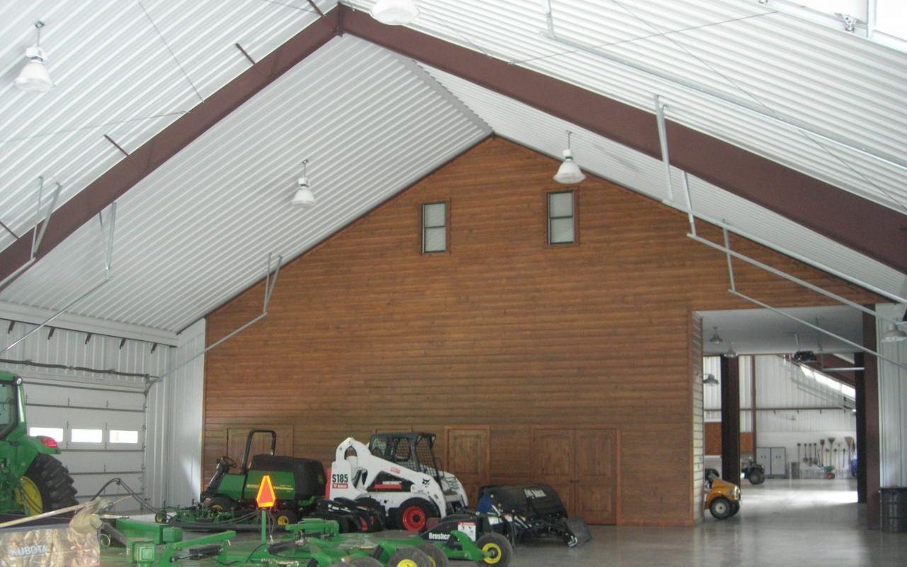 Barndominium shop with wood-paneled walls and room for mowers and equipment, built by Cross Creek