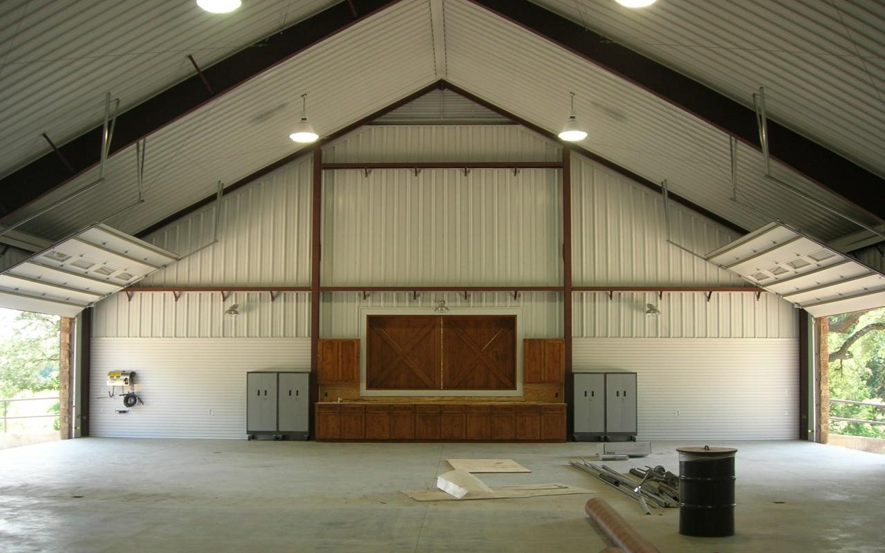 Open barndominium shop interior with steel trusses, built by Cross Creek