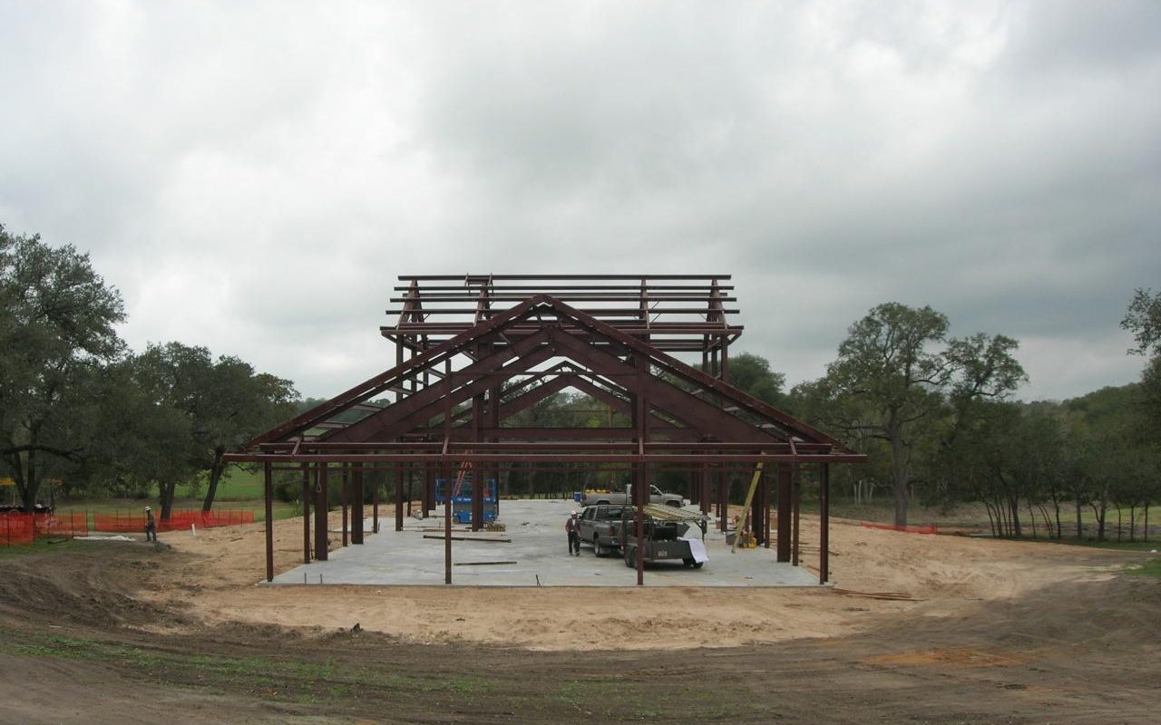 Steel frame of a barndominium going up on a concrete slab, built by Cross Creek