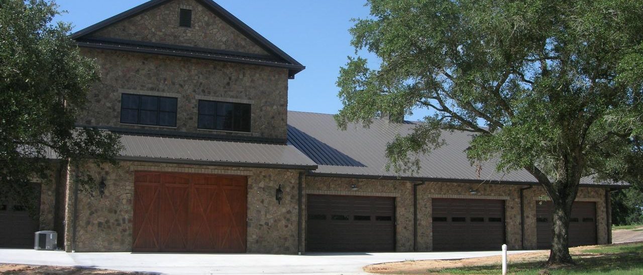 Stone barndominium with three shop bays and upstairs living space, built by Cross Creek