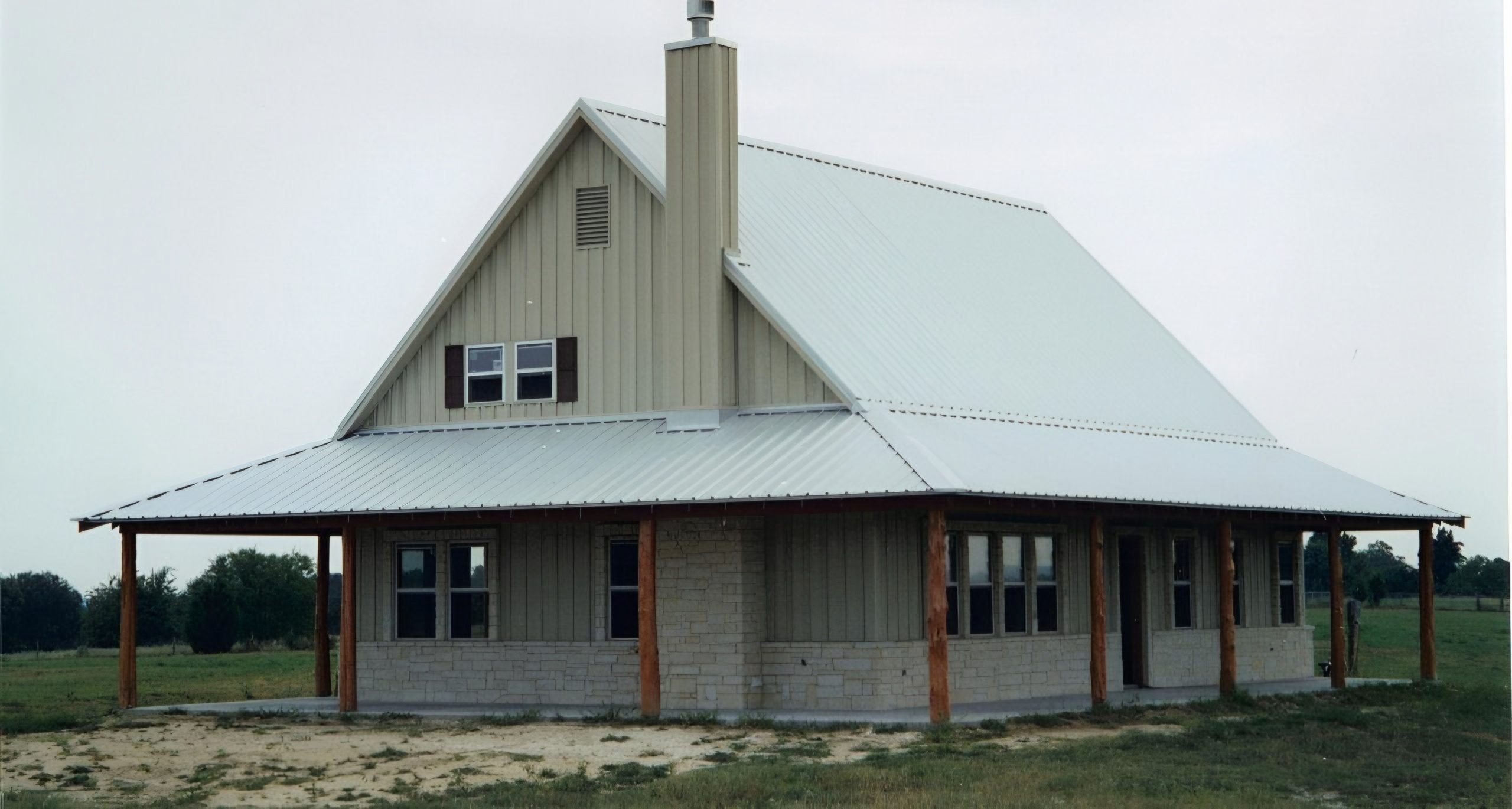 Custom barndominium with a wraparound porch on open land, built by Cross Creek Construction
