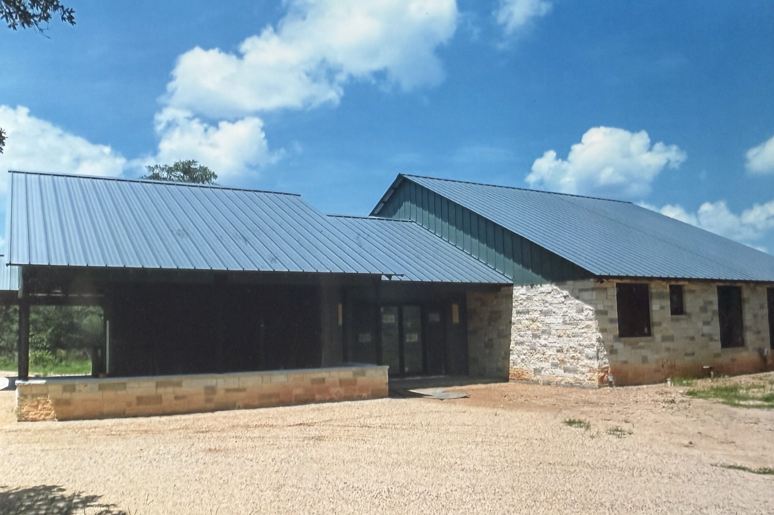 Custom stone home with a standing seam metal roof and covered porch under construction, built by Cross Creek