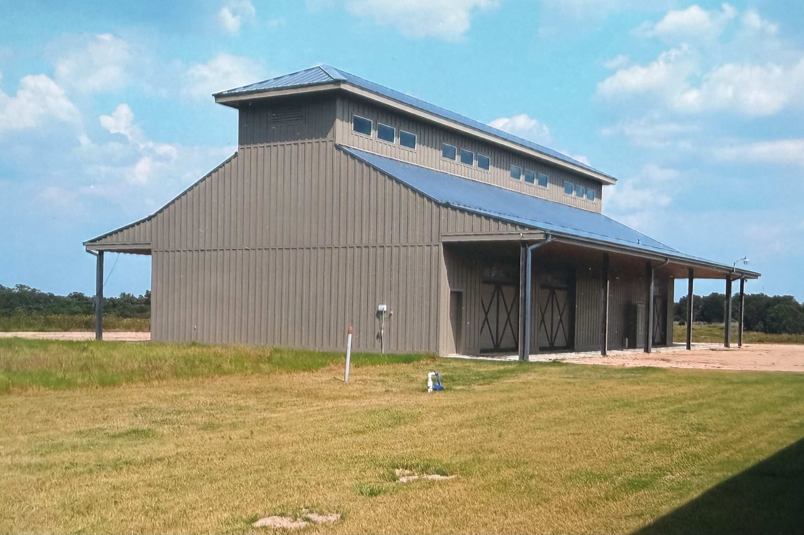 Tan metal equipment building with a raised center section and covered side porches, built by Cross Creek