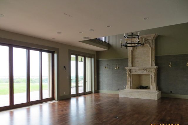 Great room with stone fireplace and wall of windows in the Perma Vista custom home
