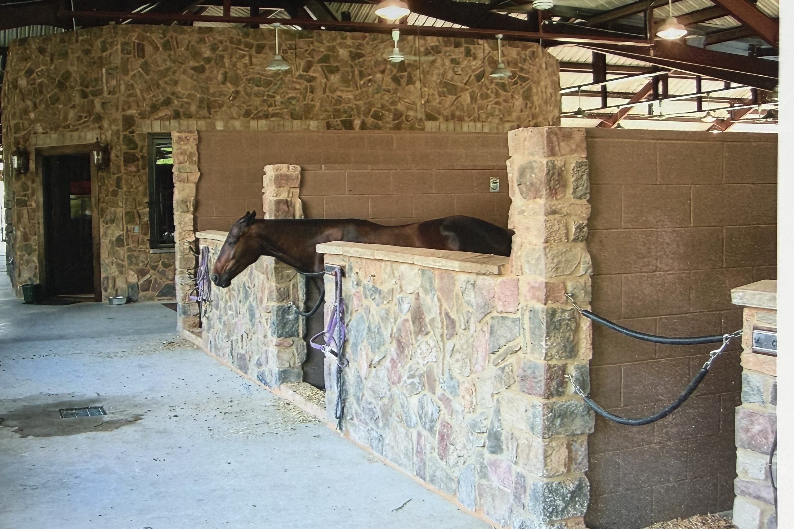 Stone and block horse stalls inside a barn, built by Cross Creek